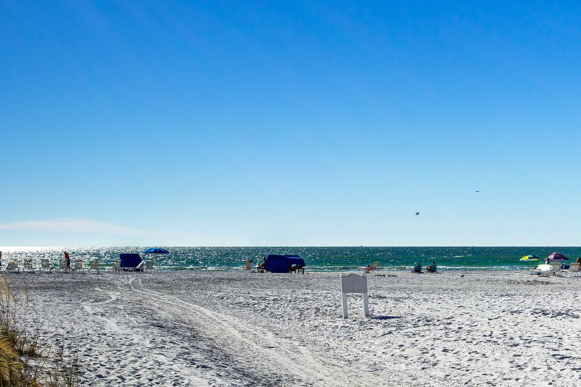 A sandy beach with several umbrellas and beach chairs.