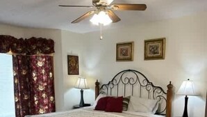 A bedroom with a bed, two bedside tables, a ceiling fan, and a window with curtains. - Patoka Lake Luxury Home #21 at Patoka 4 Seasons Resort (Eckerty)