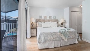 A bedroom with a large bed, two bedside tables with lamps, a ceiling fan, and a view of a balcony. - Key Point Village - Stickney Point (Sarasota)