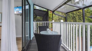 A covered outdoor area with a glass table and chairs, a white railing, and a view of greenery. - Key Point Village - Stickney Point (Sarasota)
