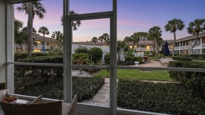 A view from a window overlooking a courtyard with palm trees and a building with balconies. - Kingston Arms 1st Floor (Sarasota)