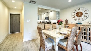 A dining area with a wooden table, wicker chairs, and a large wall clock. - Kingston Arms 1st Floor (Sarasota)