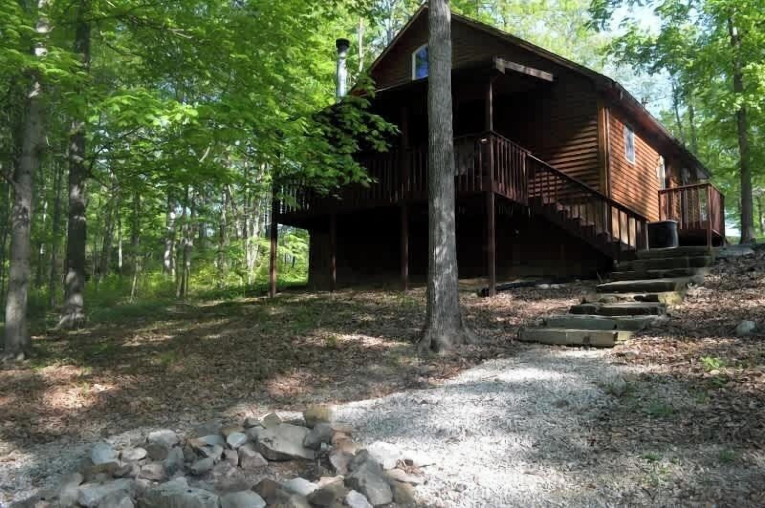 A rustic cabin with a wooden exterior, a porch, and a staircase leading up to the entrance.