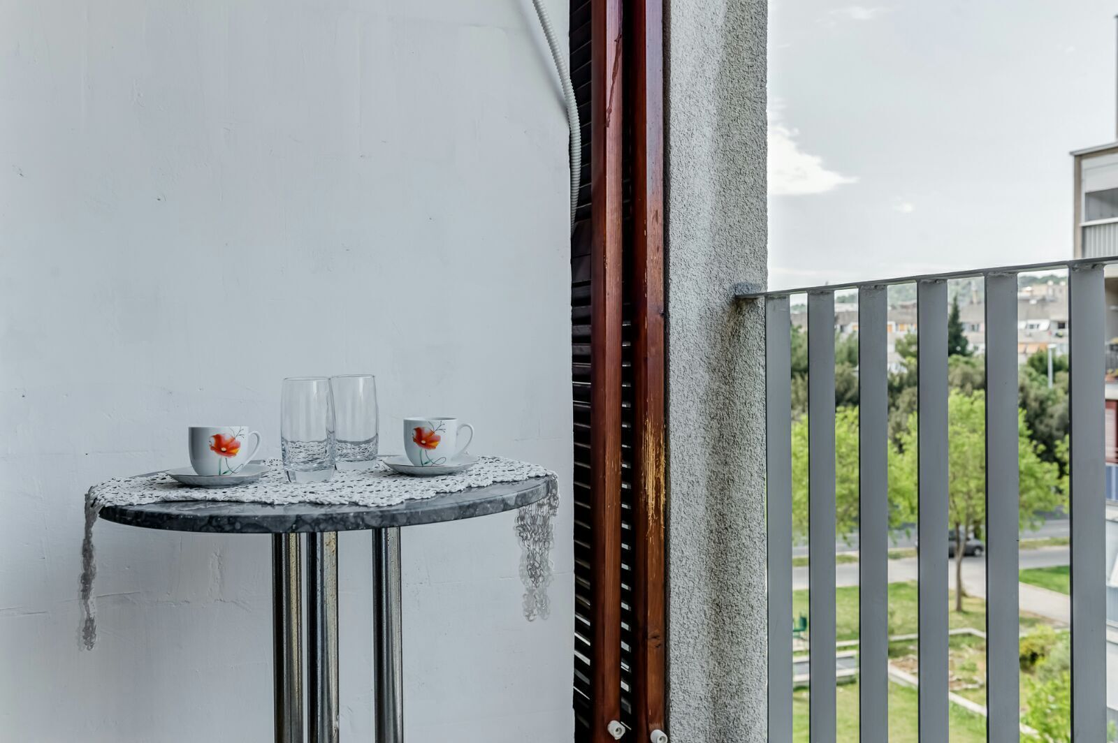 Un balcon avec une petite table ronde, deux tasses et deux verres.