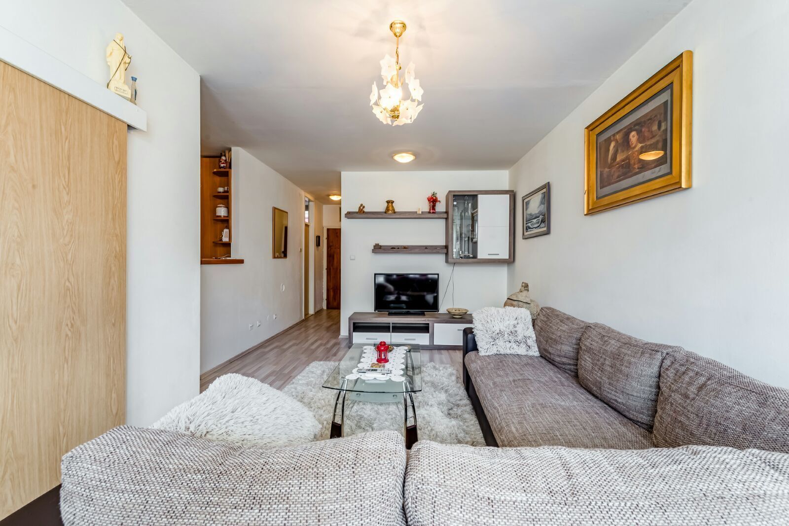 A modern living room with a sofa set, a glass coffee table, a fireplace, and a television.