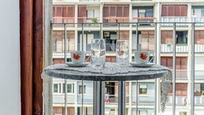 Ein Balkon mit Tisch, gedeckt für zwei Personen, mit einer klaren Karaffe, zwei Tassen mit floralem Dekor und passenden Untertassen.