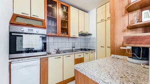 Eine Küche mit Holzausstattung, einem eingebauten Ofen, einer Spüle und einer Arbeitsplatte aus Granit.