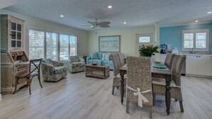 A spacious living area with a dining table, wicker chairs, a blue sofa, and a ceiling fan. - Lulu's Key House Loggerhead 2/2 Upstairs (Siesta Key)
