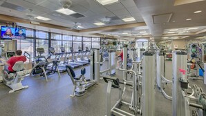 Ein Fitnessstudio mit Laufbändern, Kraftgeräten und einem Fernseher, der Nachrichten zeigt.