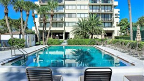 A hotel with a pool, multiple balconies, and palm trees. - Our House at the Beach Lakeside (Siesta Key)