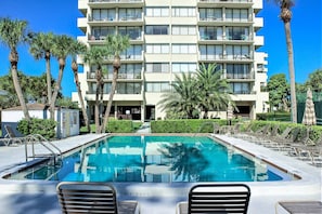 A hotel with a pool, multiple balconies, and palm trees.
