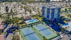 A multi-story hotel with a rooftop pool, tennis courts, and a beach view. - Our House at the Beach Lakeside (Siesta Key)