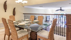 A dining area with a glass table, wicker chairs, and a ceiling fan. - Our House at the Beach Lakeside (Siesta Key)