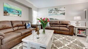 A living room with two brown leather sofas, a white coffee table with a bottle and glasses, and a rug. - Minorga in Siesta Key Village (Siesta Key)