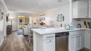 A modern kitchen with white cabinetry, a central island with a sink, and a dishwasher. - Palm Bay Club - Bayside (Siesta Key)