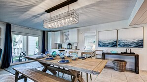 A spacious kitchen with a large wooden table, modern pendant lighting, and coastal artwork. - Palm Bay Club Bayside Closest to Gulf (Siesta Key)