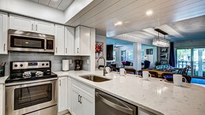 A modern kitchen with stainless steel appliances, white cabinetry, and a large island with a sink. - Palm Bay Club Bayside Closest to Gulf (Siesta Key)