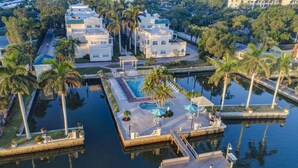 An aerial view of a resort with multiple buildings, a central swimming pool, and palm trees. - Palm Bay Club Bayside Closest to Gulf (Siesta Key)