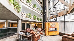 A spacious lobby with leather seating, a fireplace, and multiple levels with plants.