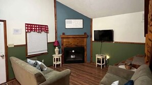 A living room with a fireplace, two sofas, a television, and a small table. - Patoka Lake Deluxe with Hot Tub #11 at Patoka 4 Seasons Resort (Eckerty)