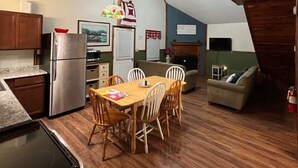 A cozy, open-plan living space with a kitchen, dining area, and seating area. - Patoka Lake Deluxe with Hot Tub #11 at Patoka 4 Seasons Resort (Eckerty)