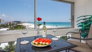 A balcony with a table set for two, featuring a bottle of wine, a glass, a plate of watermelon slices, and a red rose. - Palm Bay Club 7th-floor Oceanfront Condo on Private Beach (Siesta Key)