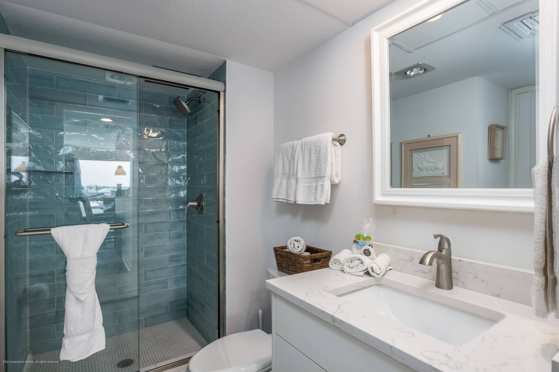 Un baño con cabina de ducha de vidrio, un lavabo blanco y un espejo grande.