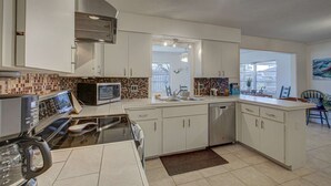 A modern kitchen with white cabinets, a black stove, a microwave, and a dishwasher. - Peaceful Egret Pool Home in Venice (Venice)