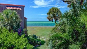 A view of a beach with a building in the foreground. - Pass Key Rd Sandy Cove II (Siesta Key)