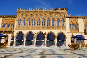 Un edificio histórico con arquitectura gótica ornamentada, que presenta una entrada central en arco y un patio con azulejos.