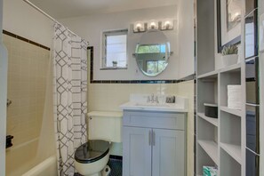 Un baño con inodoro, lavamanos, espejo y cortina de ducha.