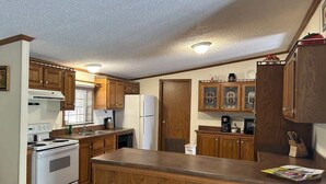 Una cocina con gabinetes de madera, una estufa blanca y un refrigerador.