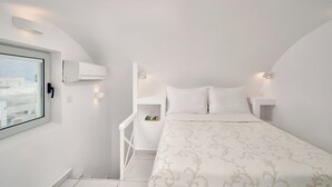 Un dormitorio con cama, paredes blancas, una ventana y techo blanco.