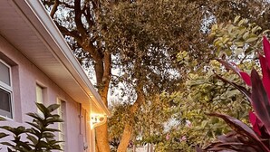 Un chemin pavé mène à un bâtiment entouré d’une clôture en bois et bordé d’arbres.