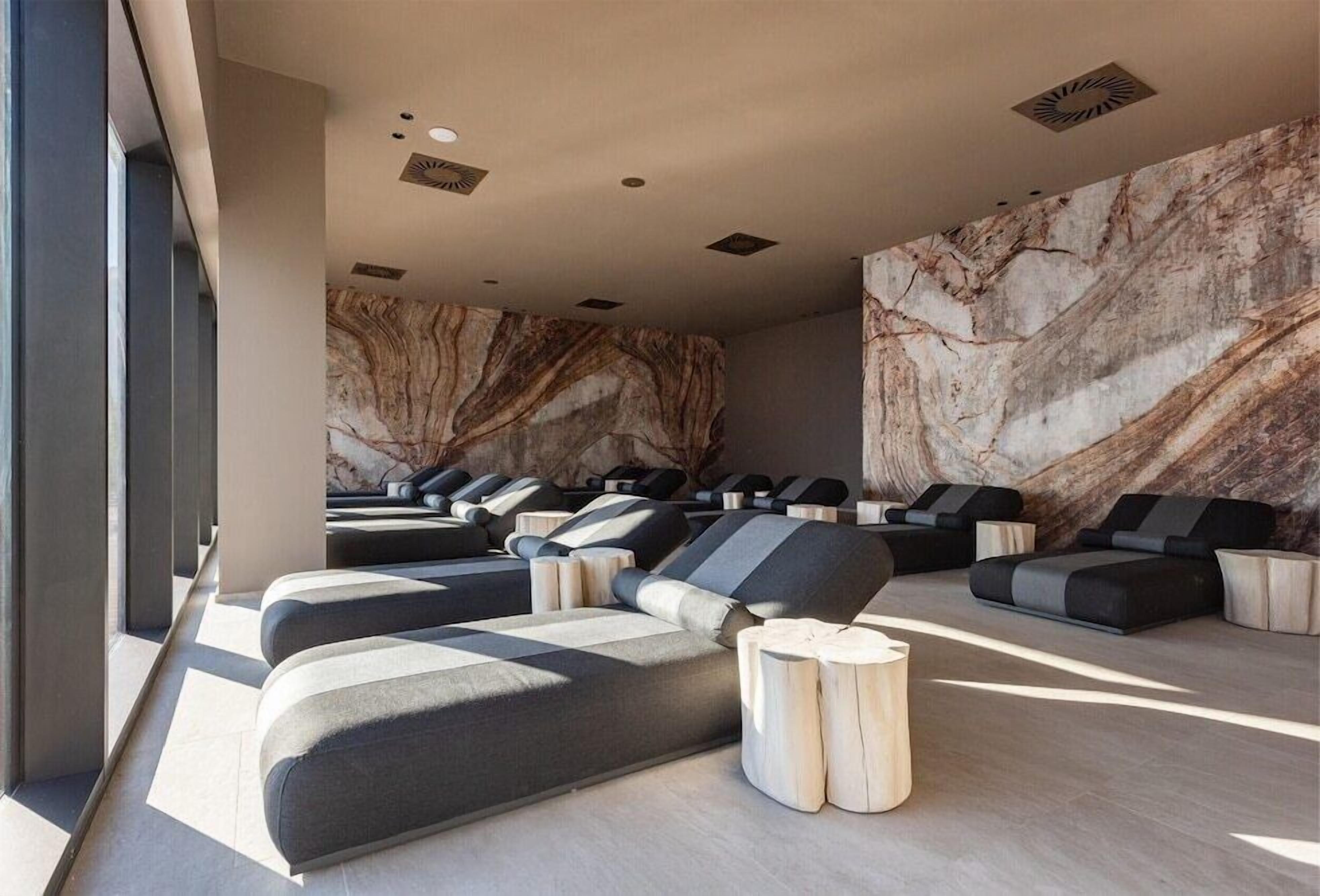 Un espace de bien-être moderne doté de fauteuils de massage, d’un mur en marbre et d’un design minimaliste.