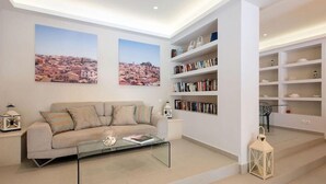 A modern living room with a sofa, coffee table, bookshelves, and decorative items. - Melina Bay Boutique Hotel (Corfu)