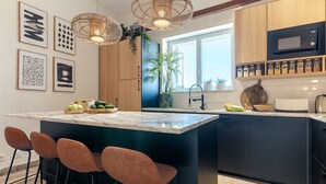 A modern kitchen with a large island, bar stools, a microwave, and a variety of jars on the shelves. - Carregado House close to Lisbon (Carregado)
