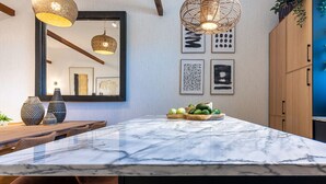 A kitchen with a marble island, wooden cabinets, and hanging pendant lights. - Carregado House close to Lisbon (Carregado)
