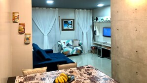 Een woonkamer met een blauwe bank, een eettafel met een banaan en een limoen, en een televisie op een meubel.