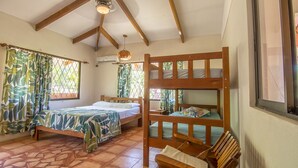 Une chambre avec deux lits, un lit superposé, une fenêtre avec des rideaux, un luminaire suspendu et un sol carrelé.