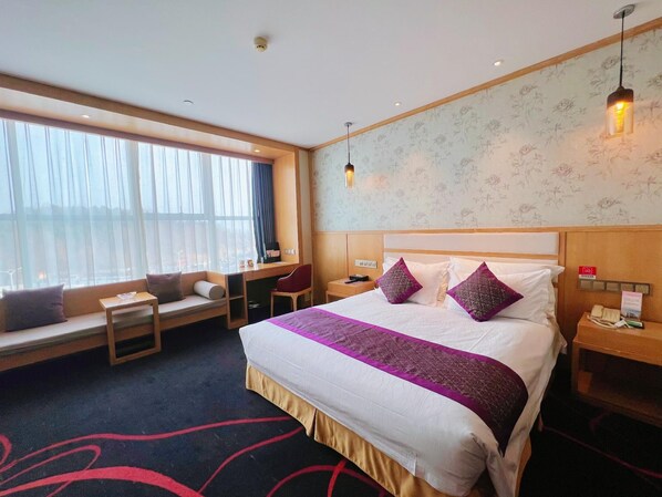 Una habitación de hotel con una cama grande, un escritorio y una ventana con cortinas.