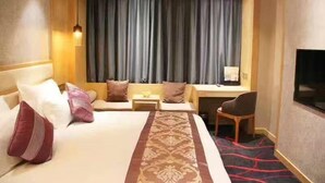 Una habitación de hotel con una cama grande, un escritorio, una silla y un televisor.