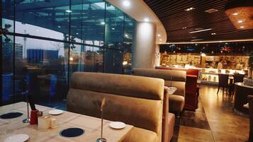 A restaurant with booth seating, a view of the city through large windows, and a modern interior design.