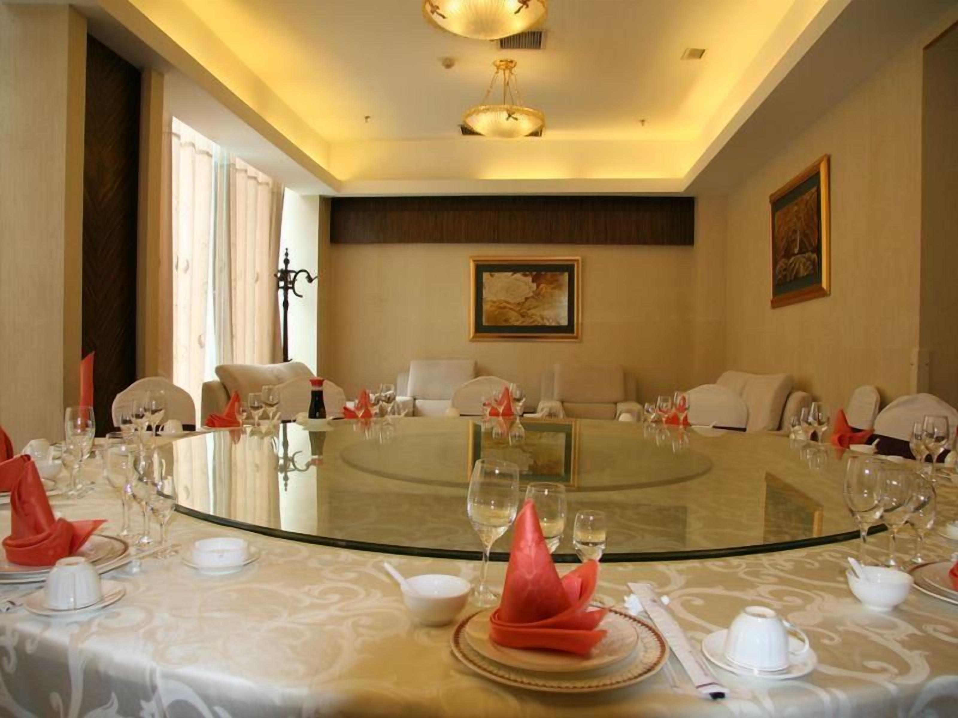 Un salón de conferencias con una mesa de cristal rodeada de sillas, una lámpara de araña y obras de arte en las paredes.
