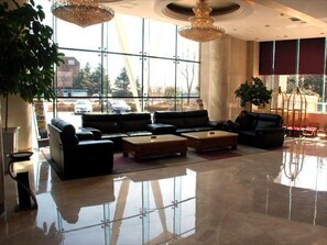 Un vestíbulo amplio con una zona de estar grande, un candelabro y vistas a través de amplias ventanas.