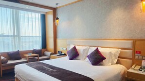 Ein Hotelzimmer mit einem großen Bett, einer Couch, einem kleinen Tisch und einem Nachttisch mit Telefon.