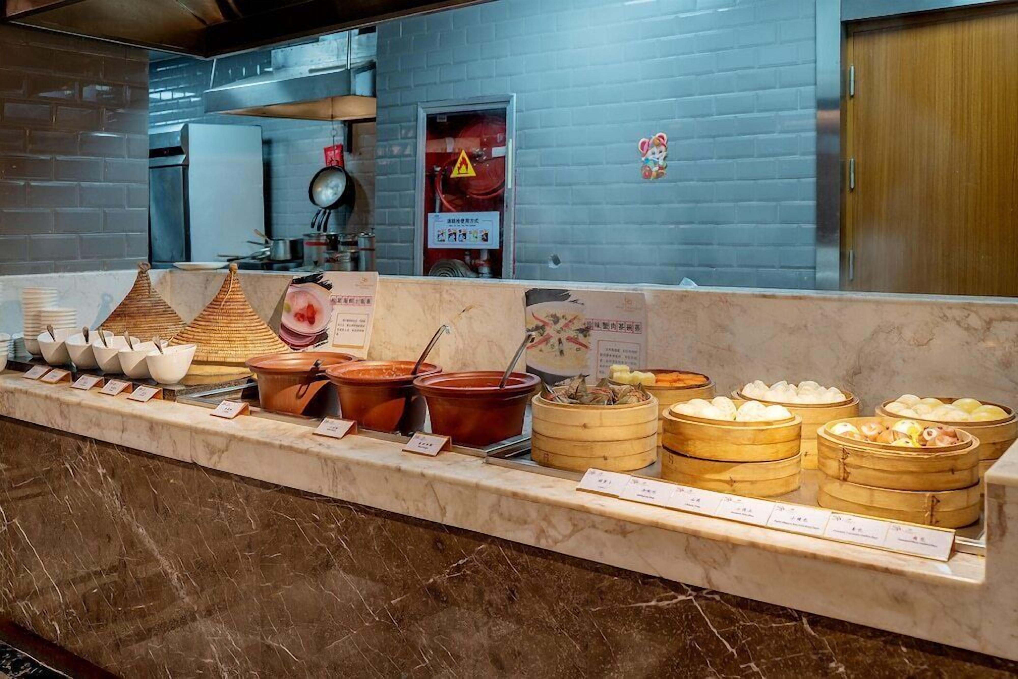 A buffet counter with various food items and a fire extinguisher on the wall.