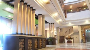 A lobby with a reception desk, a staircase, and a large window. - ZEN Rooms KH Mas Mansyur (Surabaya)
