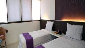 A hotel room with two beds, a small table, a chair, and a window with blinds. - ZEN Rooms KH Mas Mansyur (Surabaya)