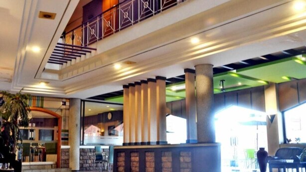 A hotel lobby with a staircase, large columns, and a reception desk. - ZEN Rooms KH Mas Mansyur (Surabaya)